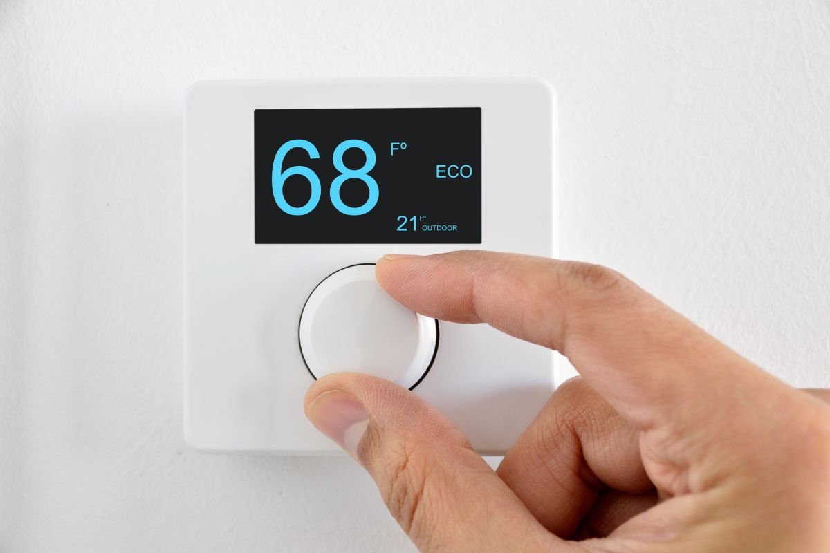 A hand adjusting a thermostat