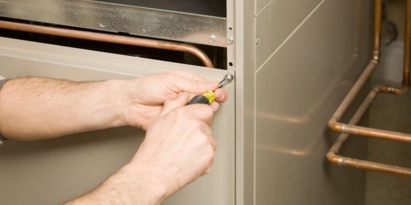 A technician opening a furnace to find where the furnace noises are coming from.