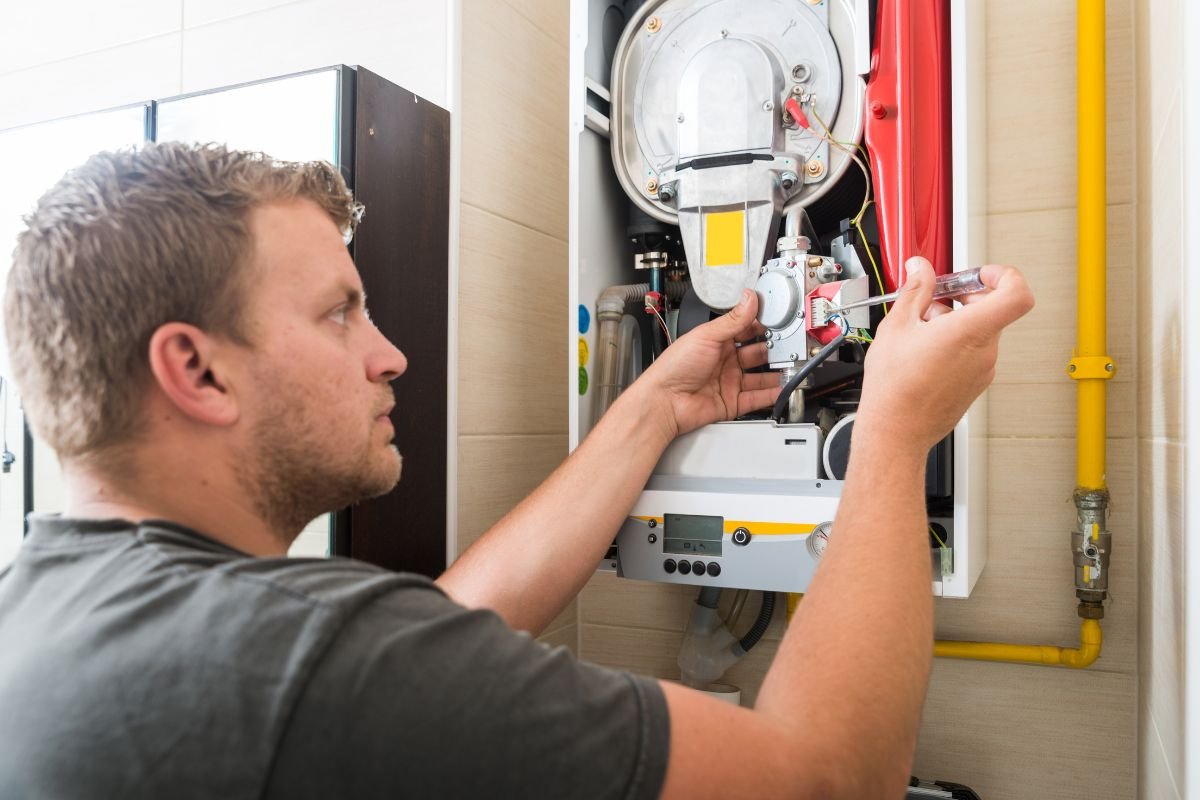 An HVAC professional fixing a furnace due to furnace noises.